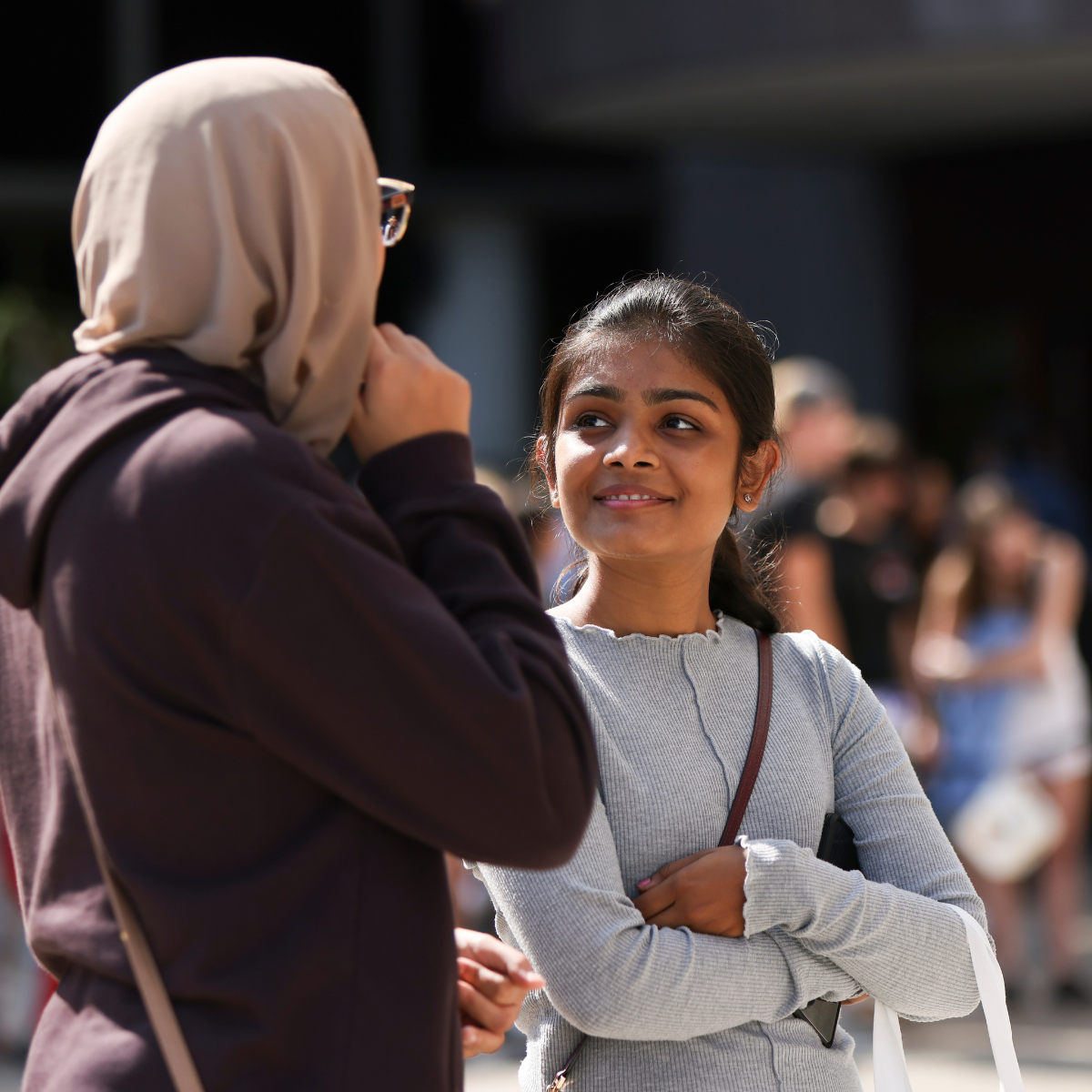 Two young ladies, one looking up at the other.